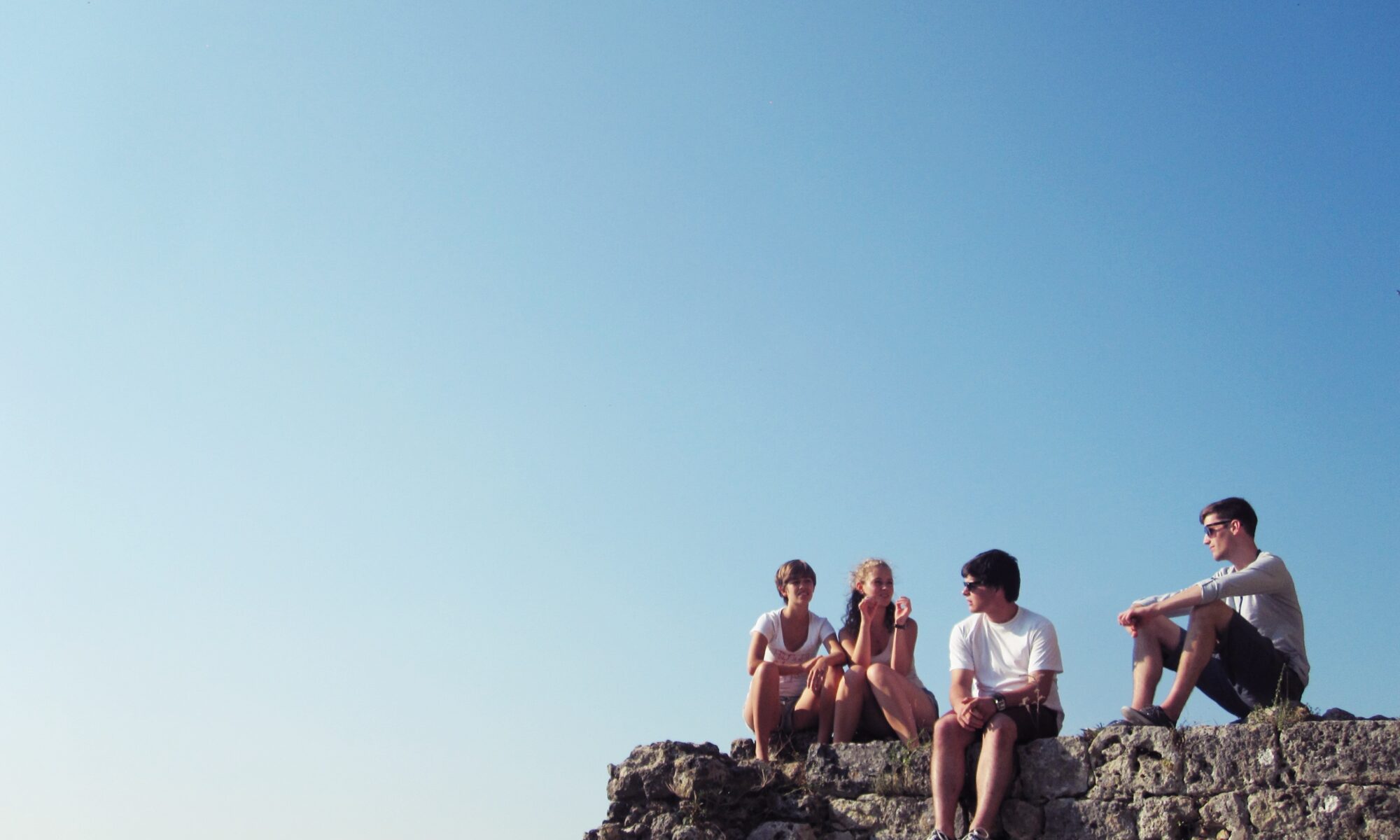Un groupe de jeunes gens assis sur un rocher sous un ciel bleu